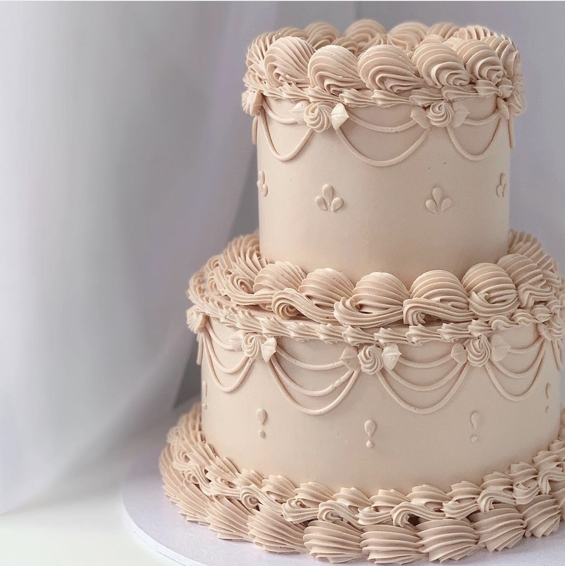 Wedding Cake vintage ivoire | Taasty Cakes Wedding Cake vintage ivoire — Un wedding cake à deux étages dans des tons ivoire, orné de volants délicats et de détails romantiques. Une pièce élégan | Taasty Cakes